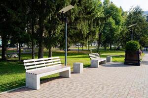 In a serene park setting, there is a row of benches positioned neatly, surrounded by lush trees that create a beautiful backdrop for visitors looking to relax and enjoy nature photo
