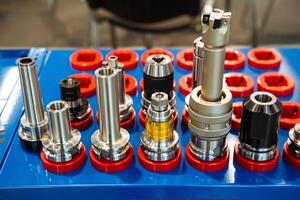 On a blue table, there is an assortment of various types of drill bits, each with a unique design and purpose, showcasing the diversity in tools used for drilling applications photo