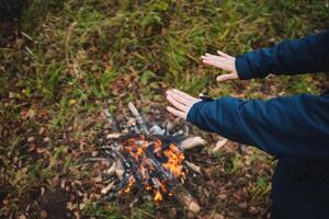 A person is warming their hands in front of a cozy fire, feeling the comforting heat radiating from the flames while enjoying the natural surroundings and the calming ambiance photo