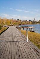 A wooden walkway leading to a lake in a park photo