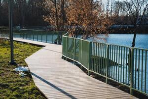 A wooden walkway leading to a lake with a green fence photo