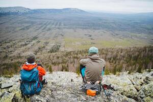 Two travelers on a hilltop admiring the sky and natural landscape photo
