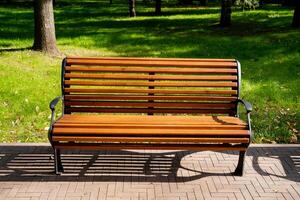A beautifully crafted wooden park bench is comfortably situated on a meticulously maintained brick sidewalk nestled within the serene and tranquil environment of a picturesque park setting photo