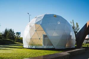 This remarkable contemporary Geodesic Dome structure is beautifully positioned within the tranquility of a lush green park environment photo