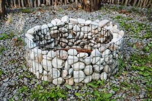 A fire pit constructed with stones and enclosed by a wire fence is a classic addition to outdoor spaces. It evokes a welcoming ambiance through its heat and allure, providing a cozy setting photo