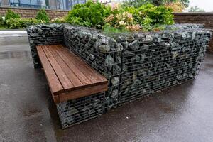 A sturdy wooden bench is comfortably placed right on top of a solid rock wall, creating an ideal location for relaxation, where one can fully enjoy the beautiful and serene surroundings photo