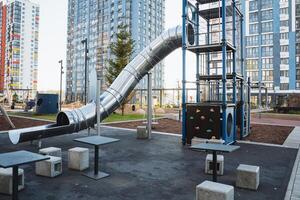 A delightful playground that features various tables and chairs arranged for comfort, alongside an exciting slide for children to enjoy and play safely during their recreational time photo
