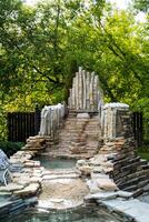 A beautiful stone bridge spans over a gentle river in a park, surrounded by lush trees. The scene elegantly combines nature with humanmade architecture, creating a harmonious blend photo
