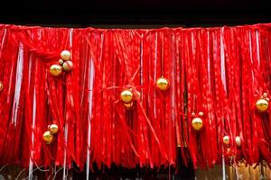 A beautiful row of vibrant red ribbons adorned with shimmering gold balls elegantly hanging from them, creating a visually stunning display that captures the essence of celebration photo
