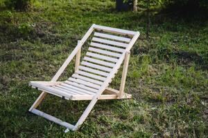 Set in a stunning outdoor location surrounded by greenery, a wooden deck chair is positioned for relaxation and comfort in a calm setting, ideal for leisure and enjoyment photo