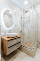 Modern bathroom with sink, mirror, and shower stall in a rectangular building photo