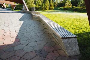 A beautifully crafted wooden bench sits on a charming brick walkway in a scenic park, surrounded by vibrant greenery inviting visitors to relax and enjoy the stunning scenery photo