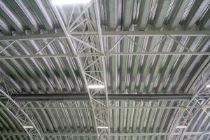 The ceiling of a large, spacious building features an intricate design with numerous metal beams that create a distinctive visual pattern, adding to the overall architectural beauty photo