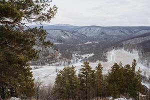 A serene valley covered in soft, white snow, bordered by evergreen trees and majestic mountains, creates a stunning winter landscape that captivates all who experience it photo
