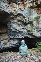 A person is sitting comfortably on the ground directly in front of a cave, taking in the beautiful scenery and completely enjoying the breathtaking natural beauty that surrounds them photo