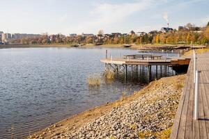 A picturesque wooden walkway stretches along the serene shore of a tranquil lake, with a charming dock visible in the background, enhancing the natural beauty of the scene photo