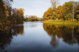 As I experience the serene autumn reflections on a calm river, I am surrounded by beautifully colorful foliage and stunning scenic nature views photo