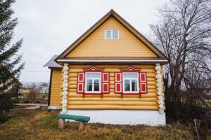 Discover the captivating charm of a yellow log cabin featuring striking red accents, beautifully set in an idyllic rural landscape photo
