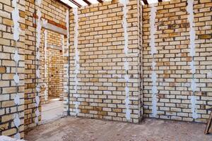 The image captures the interior of a building in progress, with a brick wall unfinished, showcasing the construction sites ongoing development and structure taking shape photo