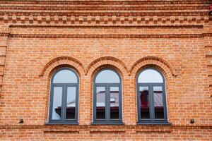 There is a brick building that features three elegant arched windows prominently displayed on one of its sides, adding charm and character to its overall aesthetic appeal photo