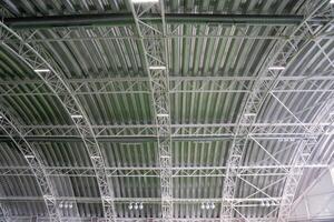 The buildings exceptionally spacious ceiling boasts intricate metal beams that contribute to a unique architectural design while effectively providing support for the entire roof structure photo