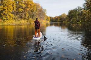 Embark on a paddleboarding adventure during the beautiful autumn season, where serene reflections grace a calm river, creating a peaceful atmosphere photo