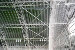 The buildings ceiling features an elaborate design with intricately arranged metal beams, providing structural support while creating a captivating aesthetic that draws attention photo