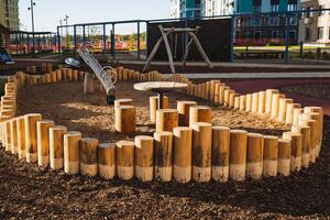 A playground featuring a fenced area constructed from sturdy logs and equipped with a table for various activities, creating a perfect space for children to play and socialize photo