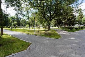 A peaceful natural landscape is created by a beautiful brick walkway in a serene park setting with lush trees and green grass. It offers a tranquil and serene environment photo