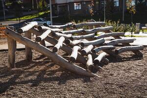 In a beautiful park, there exists an engaging playground constructed using a variety of logs and branches, offering a natural setting for fun and recreation for children and families photo