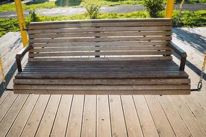 A beautifully crafted wooden swing that is securely positioned on a robust deck creates a delightful outdoor area, perfect for unwinding and appreciating the beauty of nature all around you photo