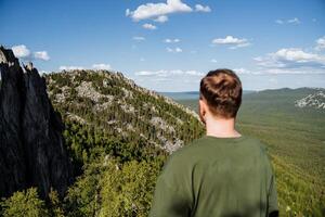 A hiker stands overlooking a breathtakingly majestic mountain view, immersed in the beauty of nature and the environment surrounding them photo