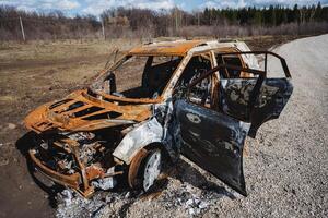 A vehicle was fired upon, a car burned to the ground on the side of the road, a rusty car body was thrown into a field. photo