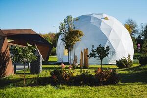 The contemporary geodesic dome structure is beautifully surrounded by thriving, lush greenery and features a variety of artistic elements photo