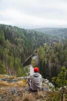 Contemplative Moment A Thoughtful Individual Wearing a Red Hat Contemplatively Overlooking a Serene and Peaceful Forest Landscape photo