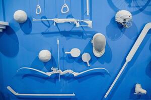 The scene features a blue wall adorned with a variety of white sports equipment that is hanging or displayed on it, creating a striking contrast in colors and showcasing multiple items photo