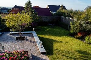An expansive aerial view capturing a beautiful backyard featuring a vibrant and lush green lawn, alongside colorful flowers dotting the landscape, creating a serene outdoor space photo