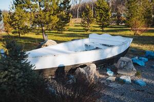 In a beautiful park, a white boat is gracefully resting on the ground, creating a striking contrast against the vibrant greenery and the natural landscapes surrounding it photo