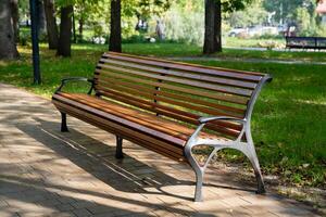 In a serene park setting, there is a charming wooden bench that invites visitors to sit and relax, with lush trees providing a beautiful backdrop, enhancing the natural beauty of the scene photo