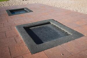 Two square trampolines are currently placed on top of a brick sidewalk, which serves as a sturdy road surface for them to rest upon, showcasing an interesting combination of materials photo