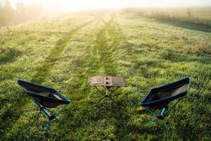 A Serene and Inviting Morning Picnic Setup in the Embrace of Nature with Comfortable Chairs and a Table photo