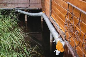 A hose is connected to a wooden building next to a body of water photo