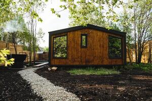 Nestled among the trees is a charming wooden cottage, blending perfectly into the natural surroundings. Its numerous windows create a tranquil and soothing environment, ideal for relaxation photo