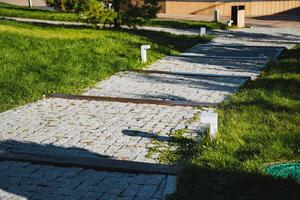 A beautiful brick walkway meanders through a lush, vibrant green field, creating a stunning contrast with the natural surroundings that enhances the overall landscape appeal photo