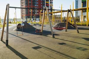 In the distance, there is an empty playground, a space where children often gather to joyfully play, situated directly in front of a building, contributing to a beautiful urban scene photo