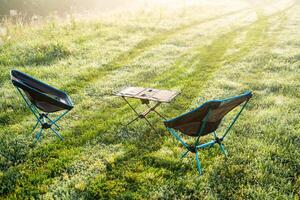 Experience the serene outdoor seating arrangement that greets you with gentle soft morning light illuminating the dewy grass in a tranquil and beautiful atmosphere photo