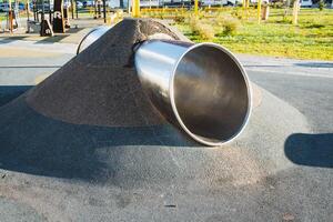 A metallic pipe is positioned on top of a substantial heap of dirt, indicating a possible construction or excavation site that involves various engineering and automotive elements photo