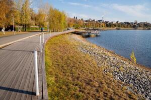 A person leisurely strolls along a lovely wooden walkway that borders a peaceful lake, taking in and appreciating the breathtaking natural beauty that surrounds this tranquil setting photo