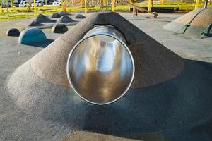 A metal pipe is going down a hill in a playground photo