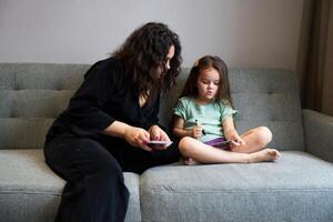 Mother and daughter engaging in creative play on a cozy gray couch at home photo